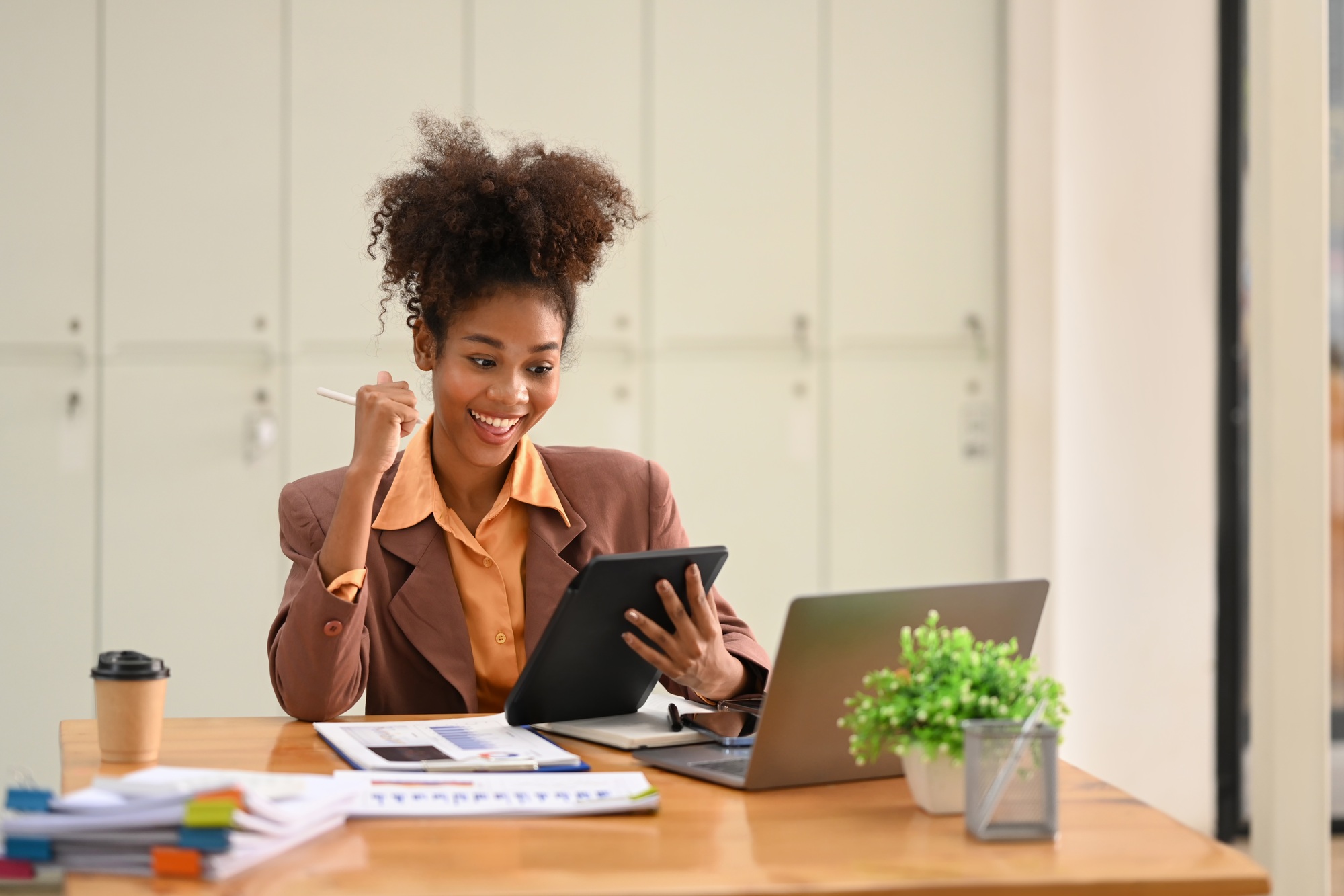 Happy African American businesswoman received good news, celebrating success.